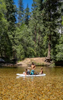 Family laughing together while paddling on a quiet river surrounded by lush greenery.