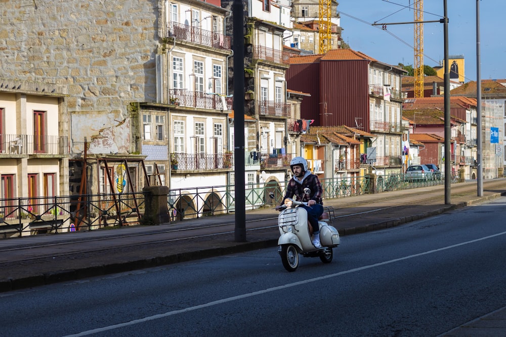 man in black jacket riding white motor scooter on road during daytime