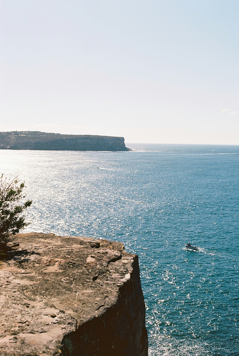 brown rocky mountain beside blue sea during daytime