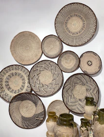 Close-up of woven wall baskets arranged artfully on a textured wall, showcasing earthy tones and craftsmanship.