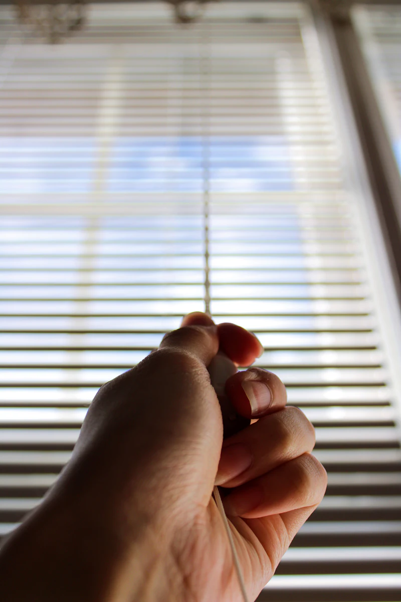 A hand adjusting the slats of a blind
