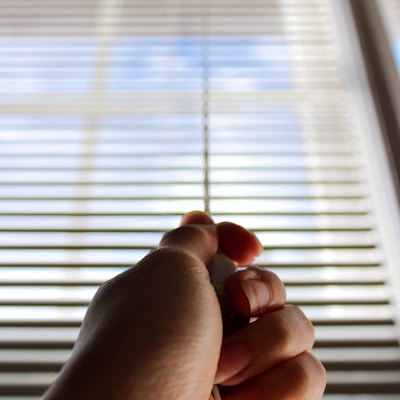 persons left hand near window blinds