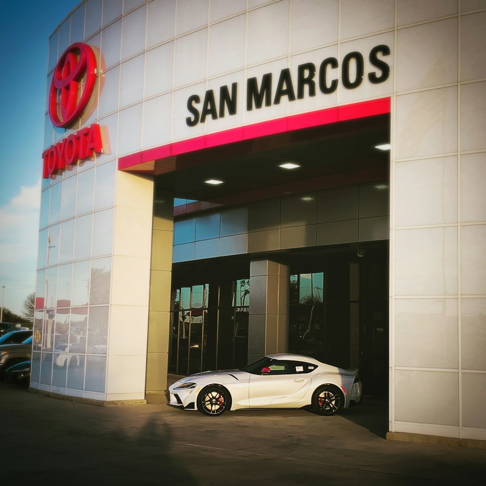 white coupe parked in front of UNKs store