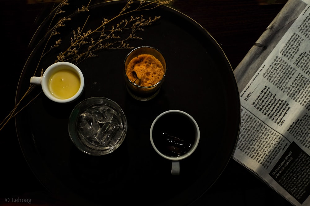 white ceramic mug on black ceramic saucer beside clear drinking glass