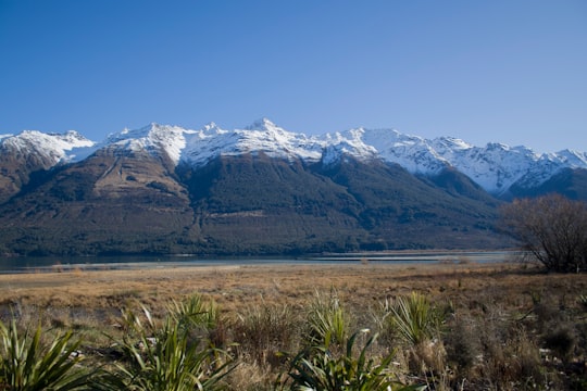 green grass field near snow covered mountains during daytime in Glenorchy New Zealand