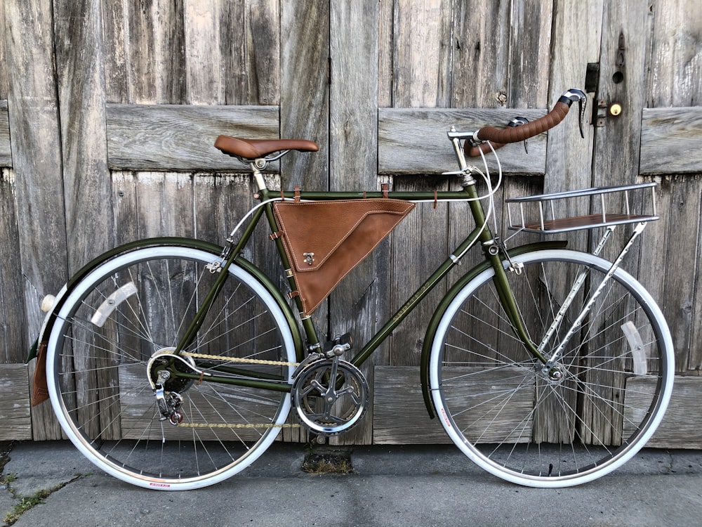 vélo de route noir et marron appuyé sur un mur en bois brun