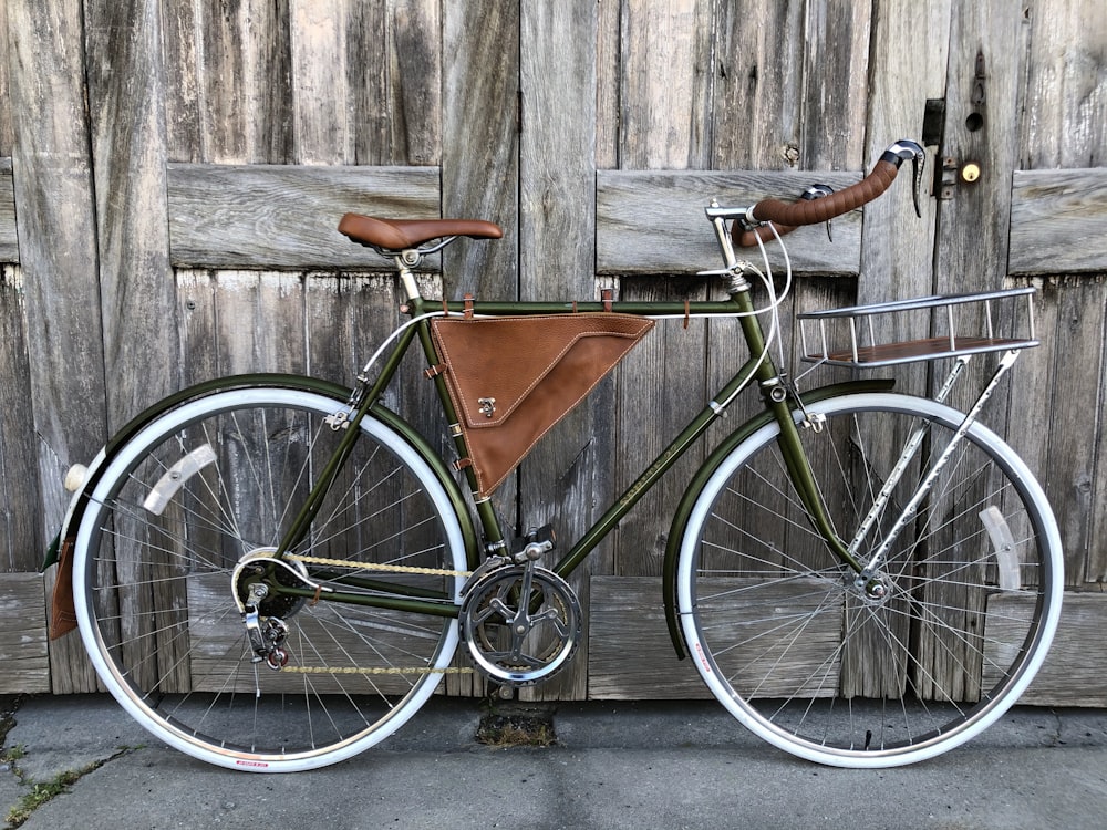 black and brown road bike leaning on brown wooden wall