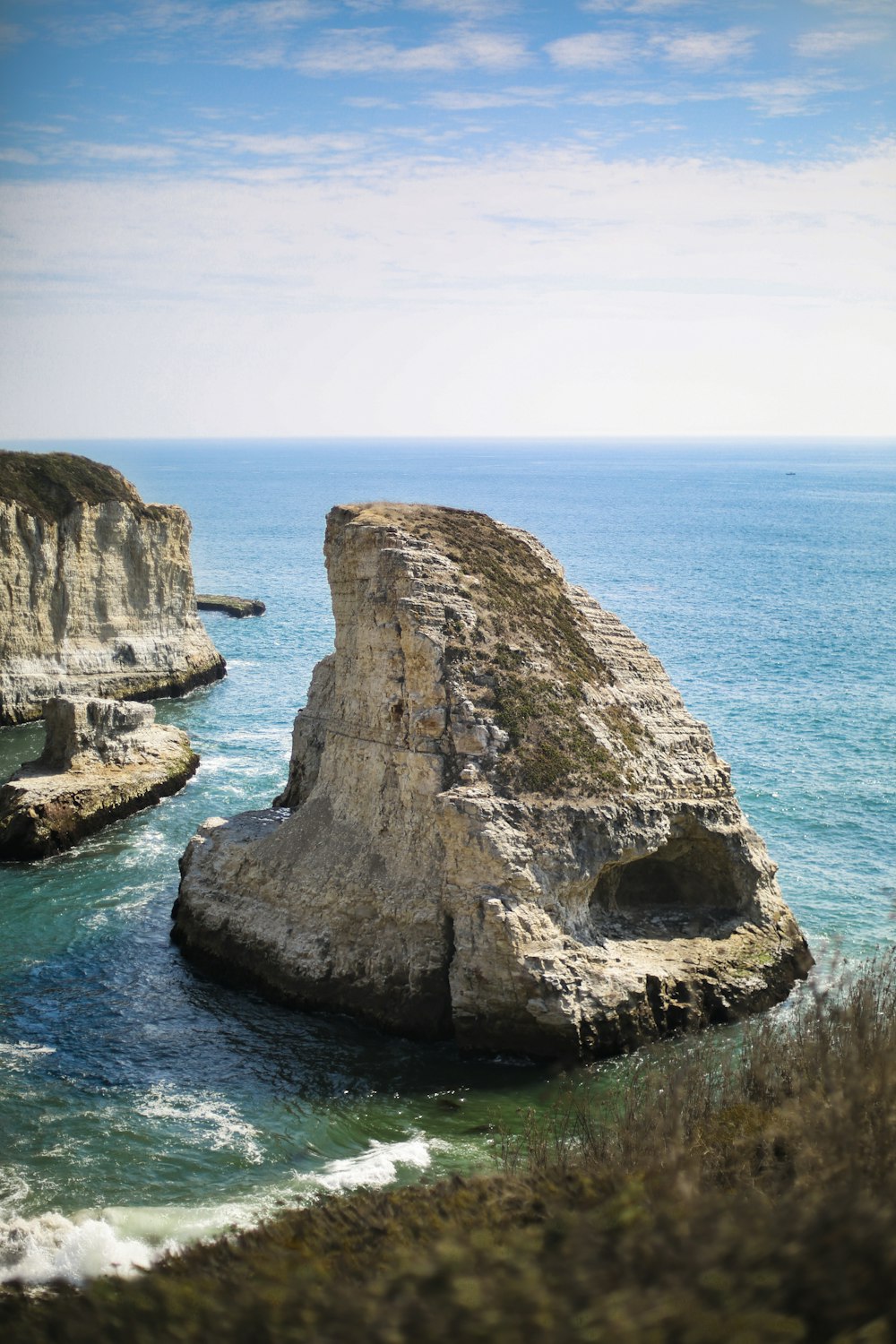 brown rock formation on blue sea under blue sky during daytime