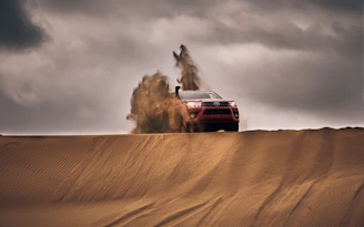 red suv on desert under gray clouds