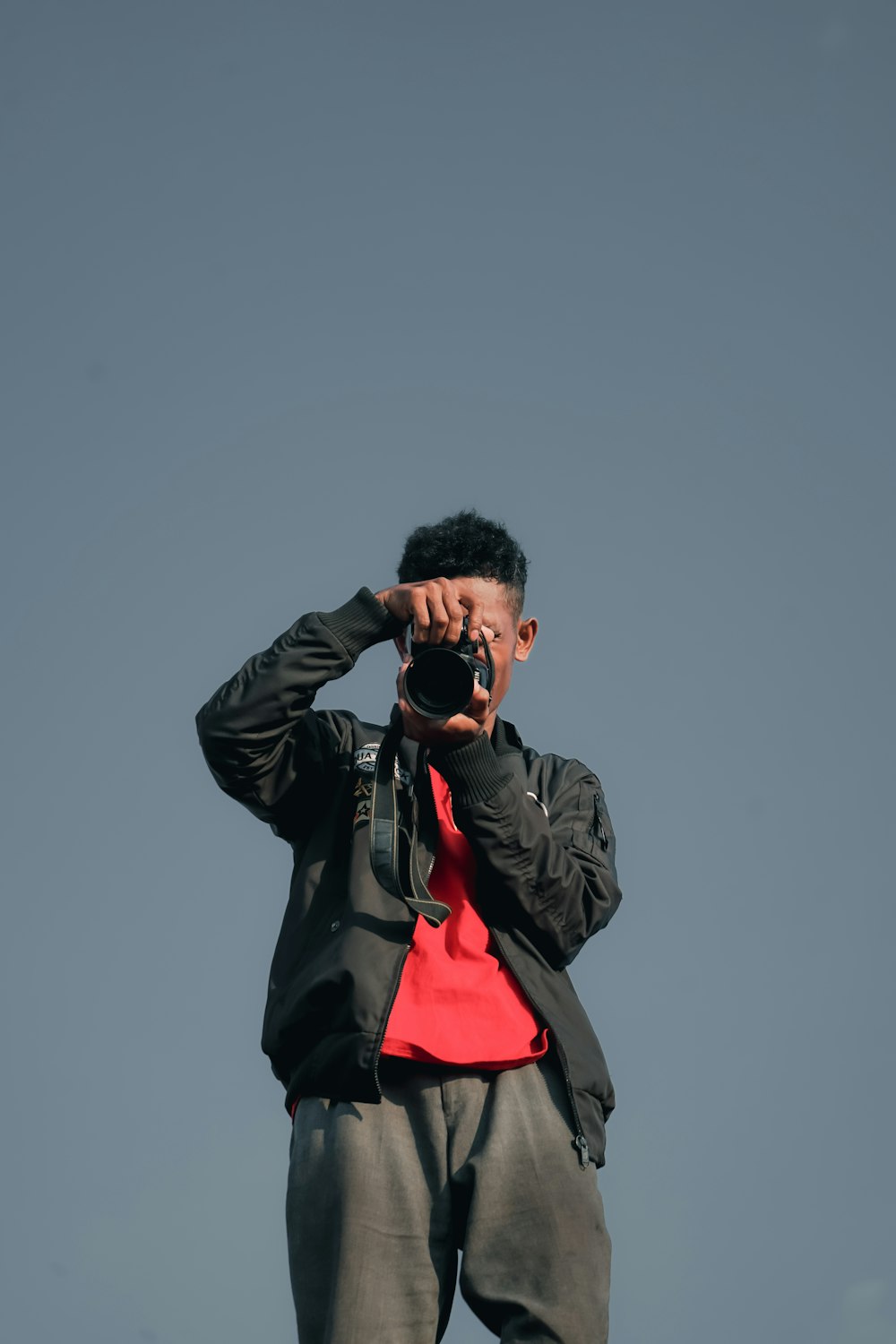 man in black leather jacket taking photo using black dslr camera