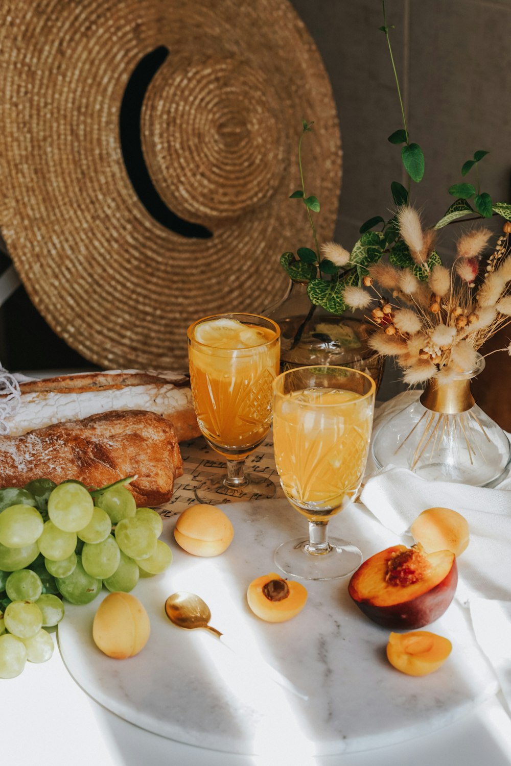 clear drinking glass with yellow liquid beside green grapes and green grapes on white table