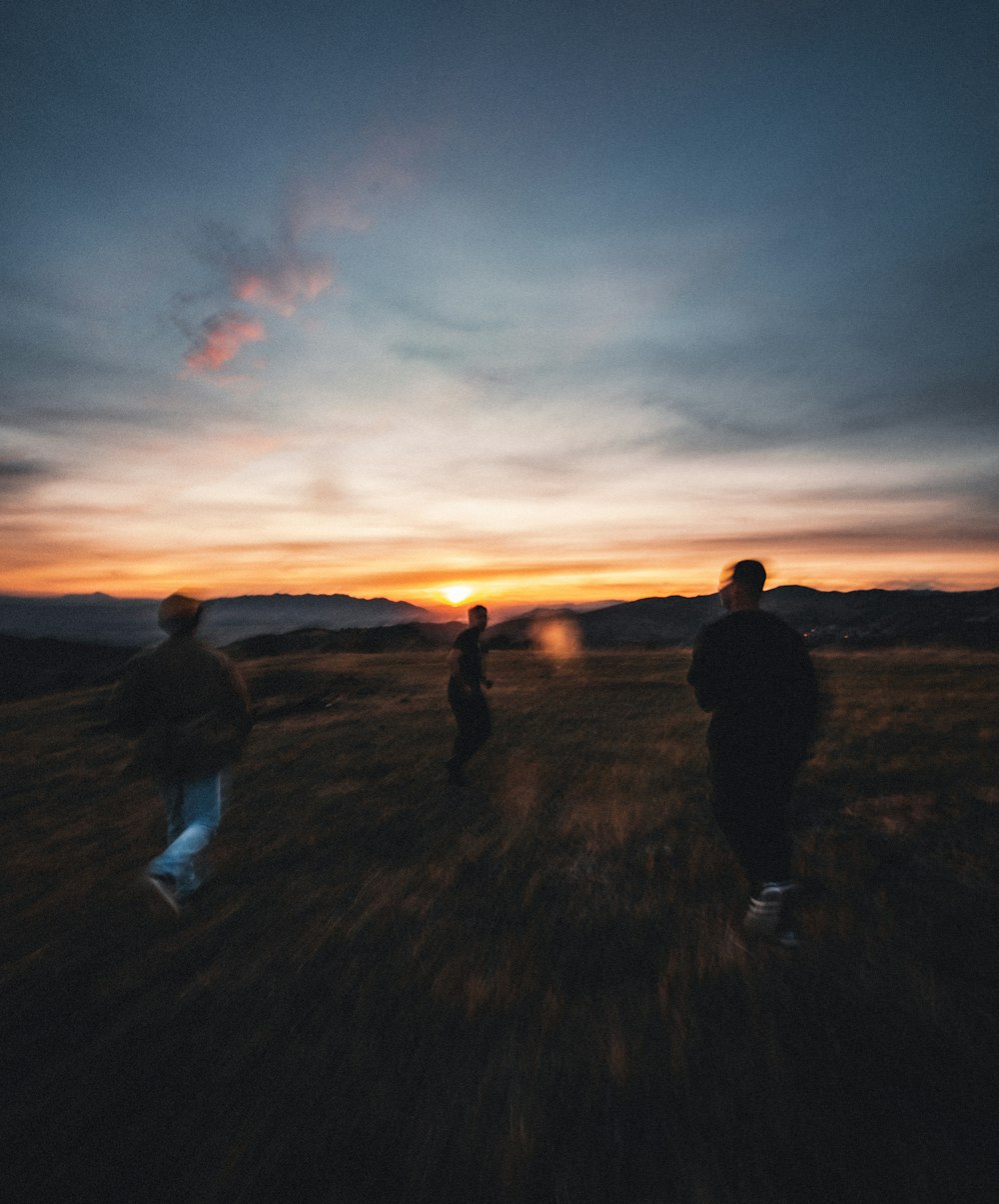 silhouette of 2 person walking on grass field during sunset