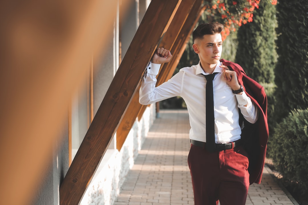 woman in white dress shirt and red pants standing beside brown wooden post