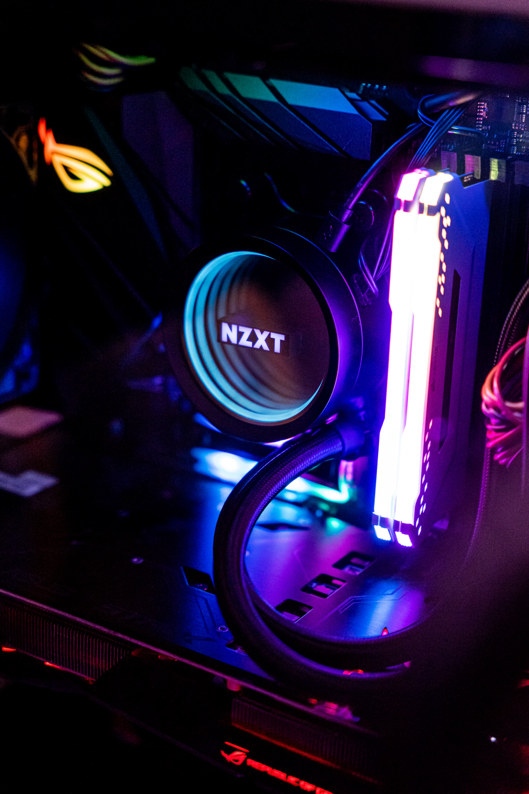 Laptop illuminated by colourful light in a dark workspace