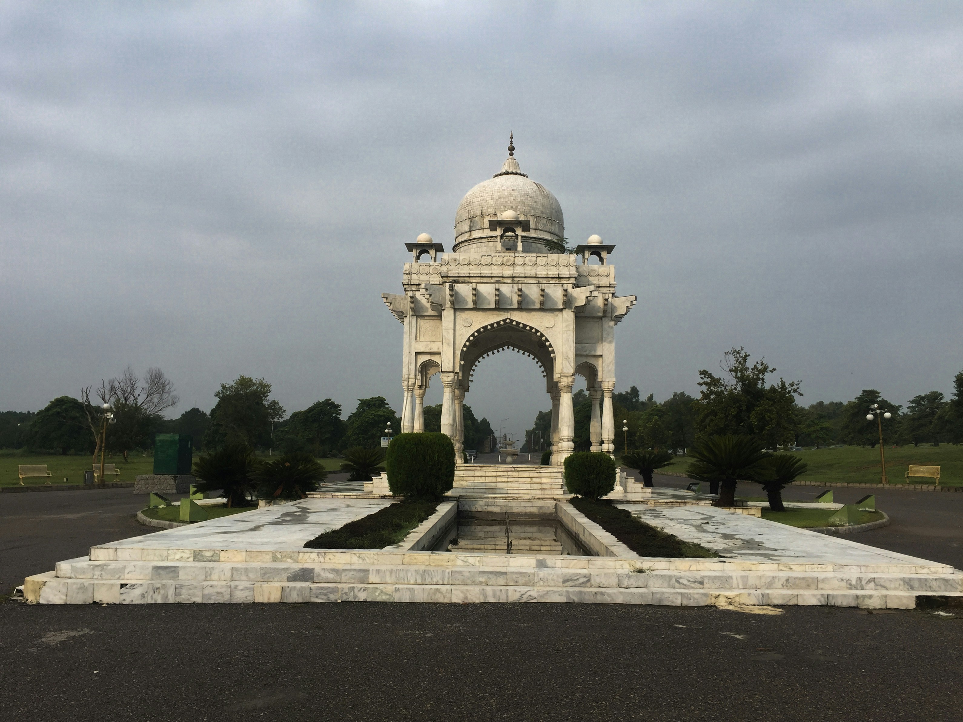 white concrete building near green trees under white clouds during daytime