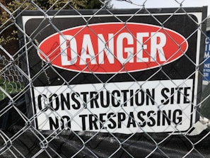 a sign on a fence that says danger construction site no trespassing