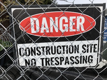 a sign on a fence that says danger construction site no trespassing
