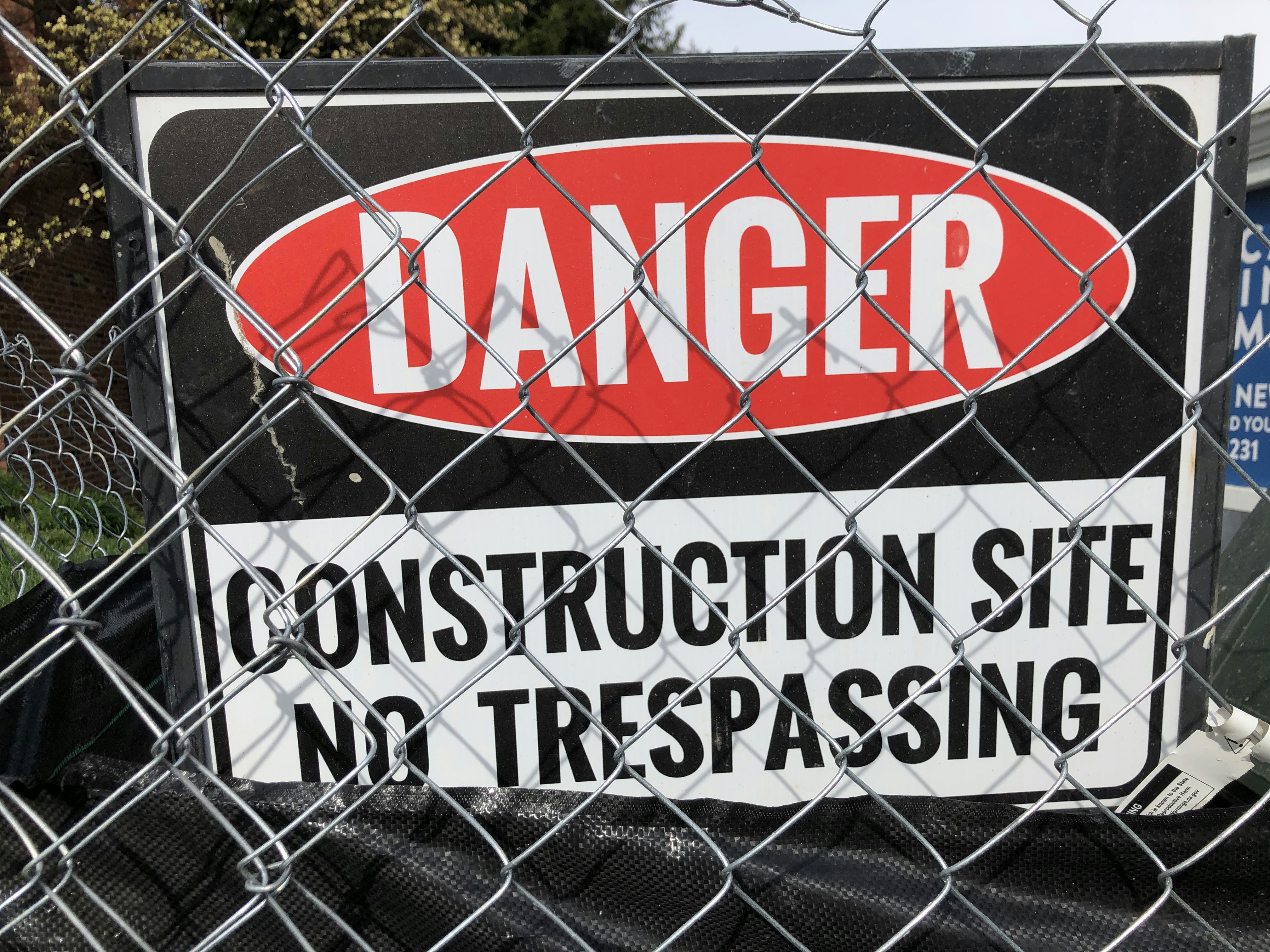 a sign on a fence that says danger construction site no trespassing