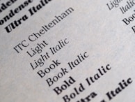A close-up of a printed page displaying various font styles and weights including Light, Light Italic, Book, Book Italic, and Bold. The text is crisp and clear, showcasing different typography samples in black ink on a light gray or beige paper.