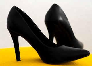 black leather heeled shoes on yellow chair