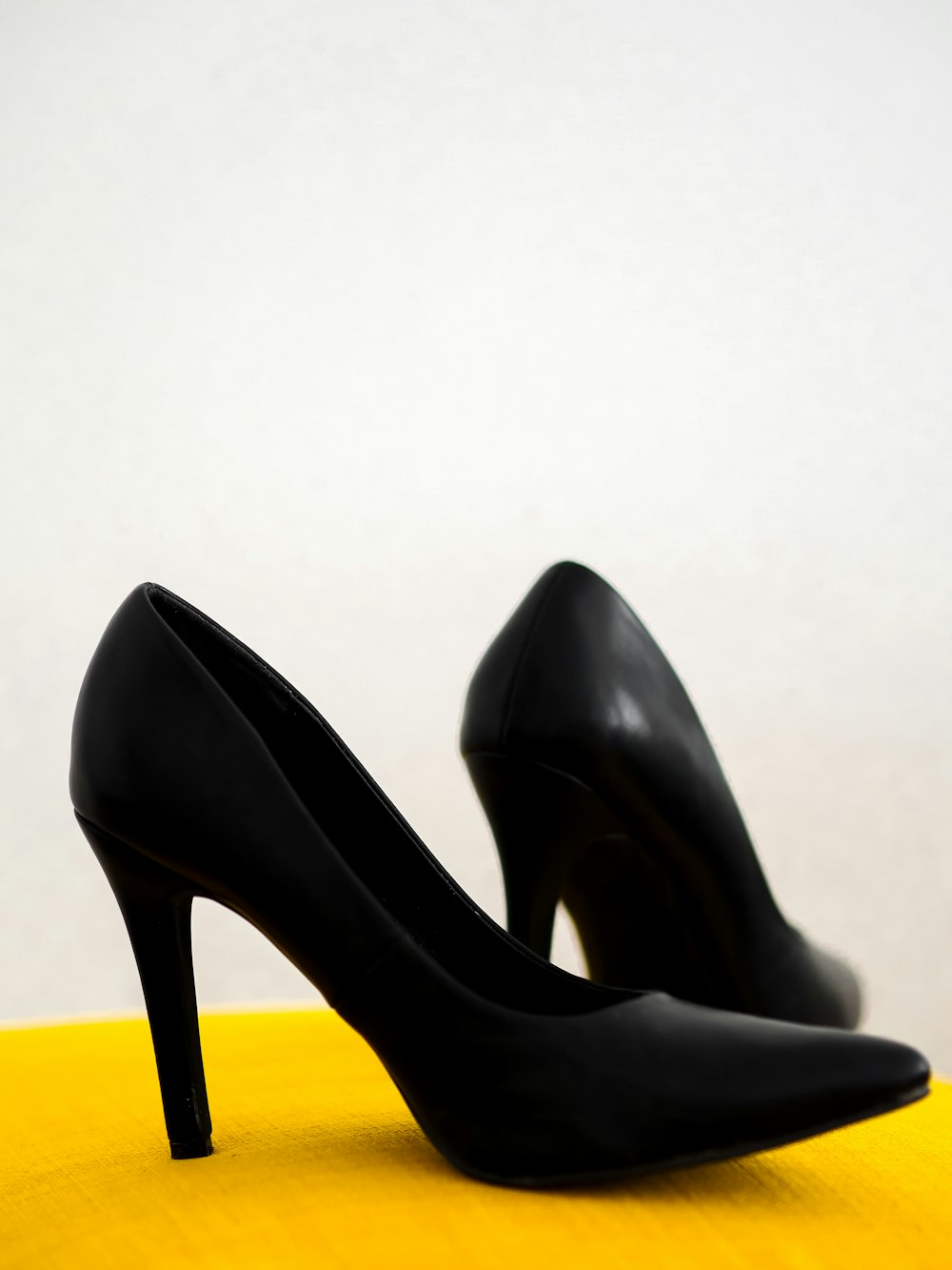 zapatos de tacón de cuero negro sobre silla amarilla