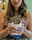 Happy woman enjoying a bowl of creamy ice cream with colorful sweets on the table.