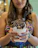 Happy woman enjoying a bowl of creamy ice cream with colorful sweets on the table.