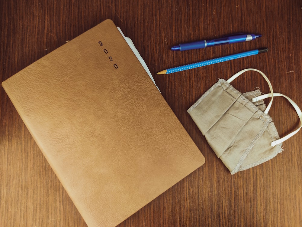 Sac en papier brun à côté du stylo à clic bleu et blanc