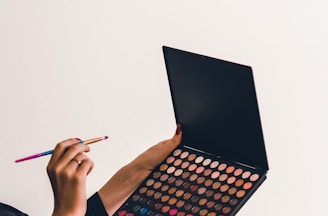 a person holding a makeup palette and a pencil