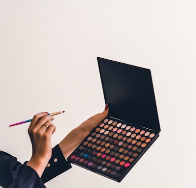 a person holding a makeup palette and a pencil