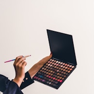 a person holding a makeup palette and a pencil