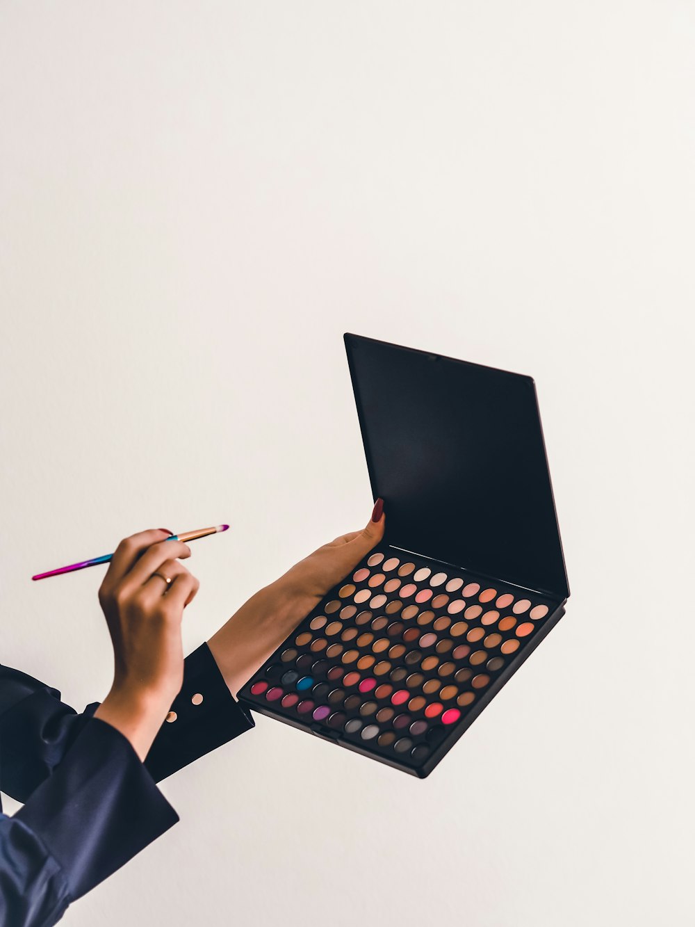 a person holding a makeup palette and a pencil