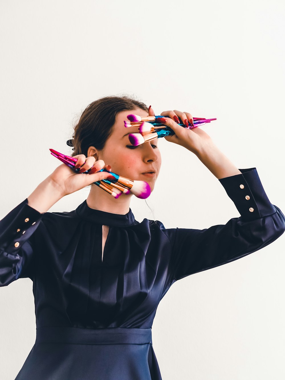 woman in black long sleeve shirt holding pink and blue pen