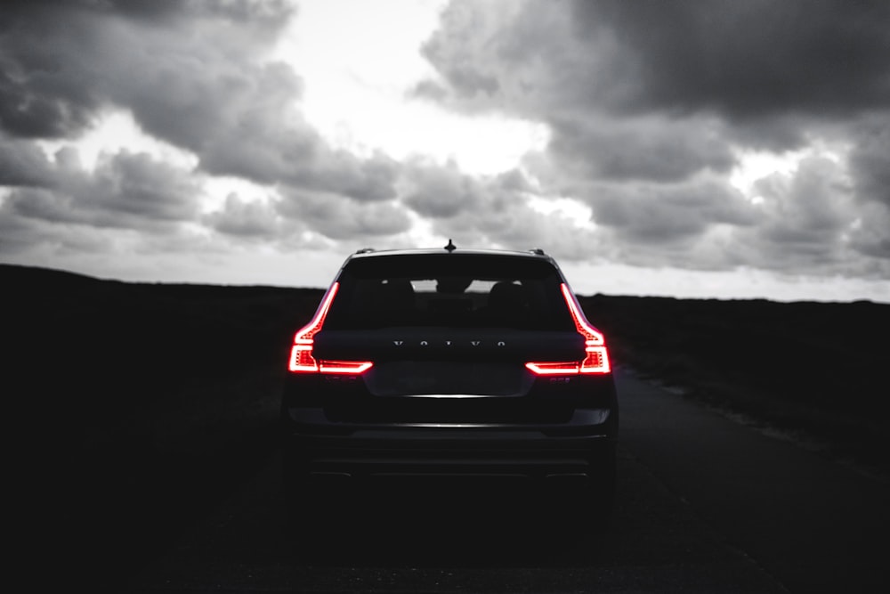 red car on black asphalt road under gray cloudy sky