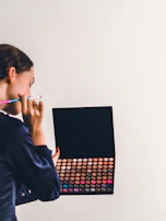 A makeup artist holding brushes and palettes, preparing for a creative look.