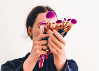 woman in black jacket holding makeup brush