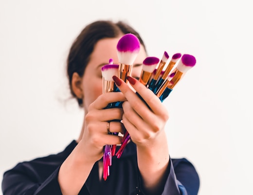 woman in black jacket holding makeup brush