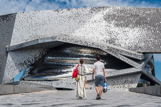 man and woman standing near white wall during daytime in La Villette France