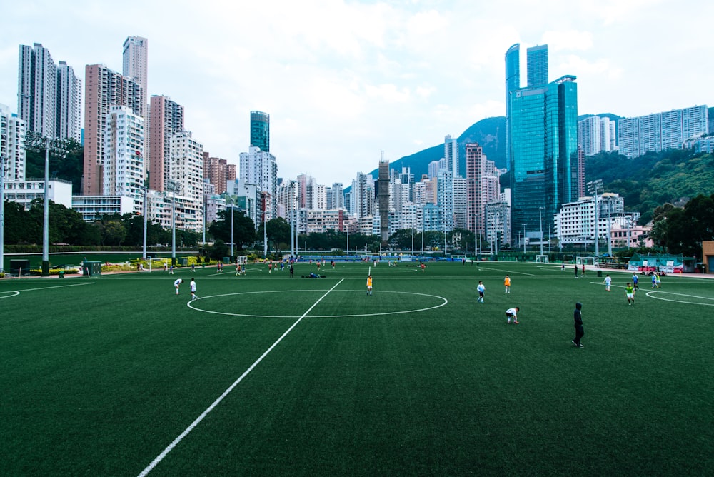 people playing soccer on green grass field during daytime