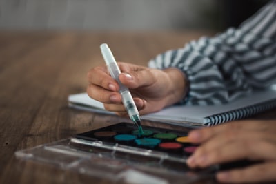 person holding white pen on brown wooden table talented zoom background