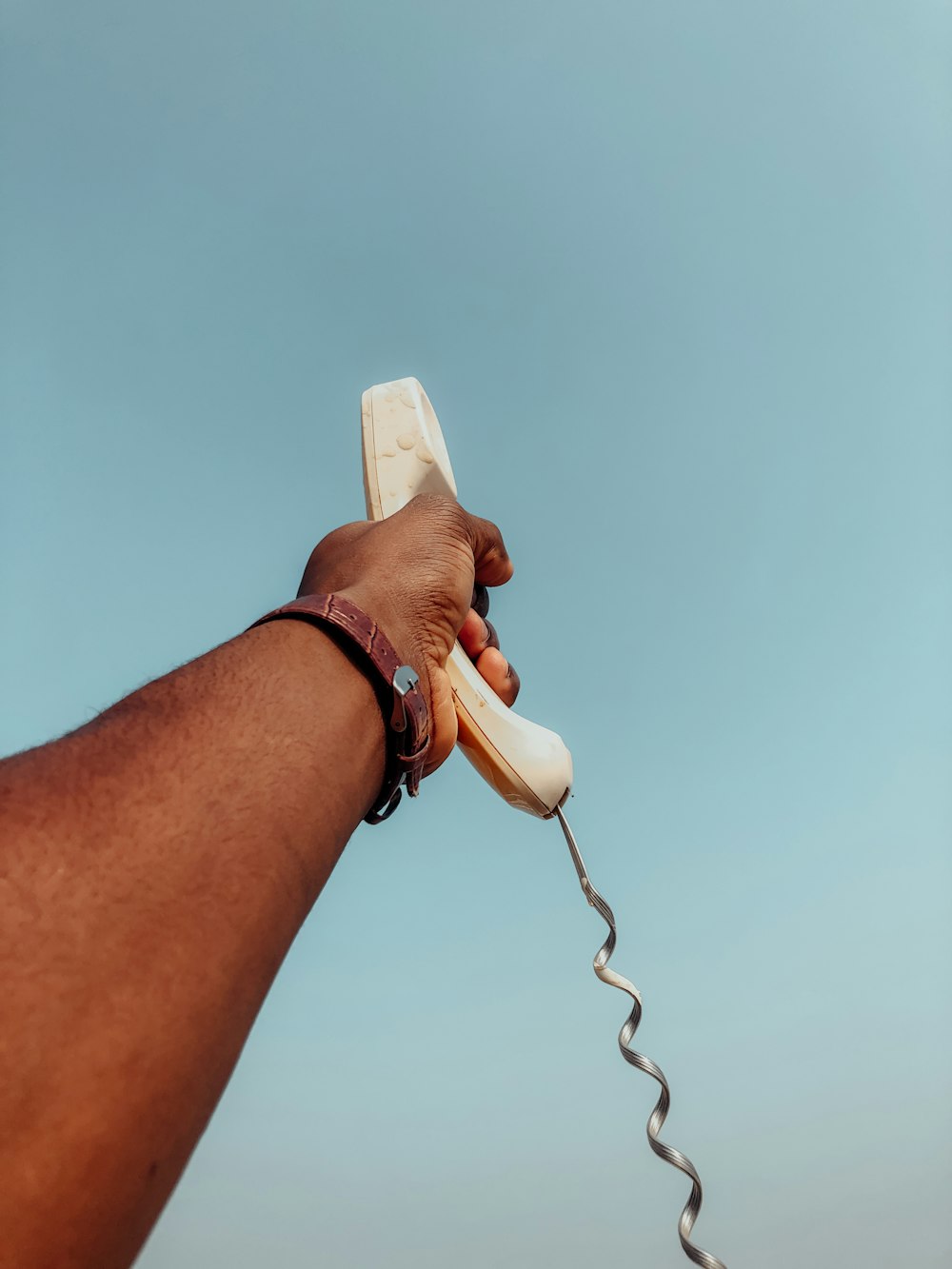 person holding white corded telephone