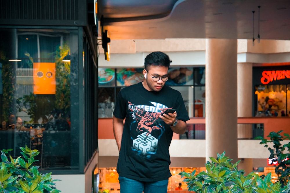 man in black crew neck t-shirt and orange shorts standing near green plant during daytime