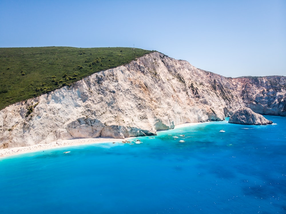 green and brown mountain beside blue sea during daytime