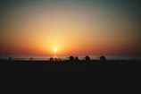 Sunset over Ipanema beach with colorful skies and silhouettes of people enjoying the shore.