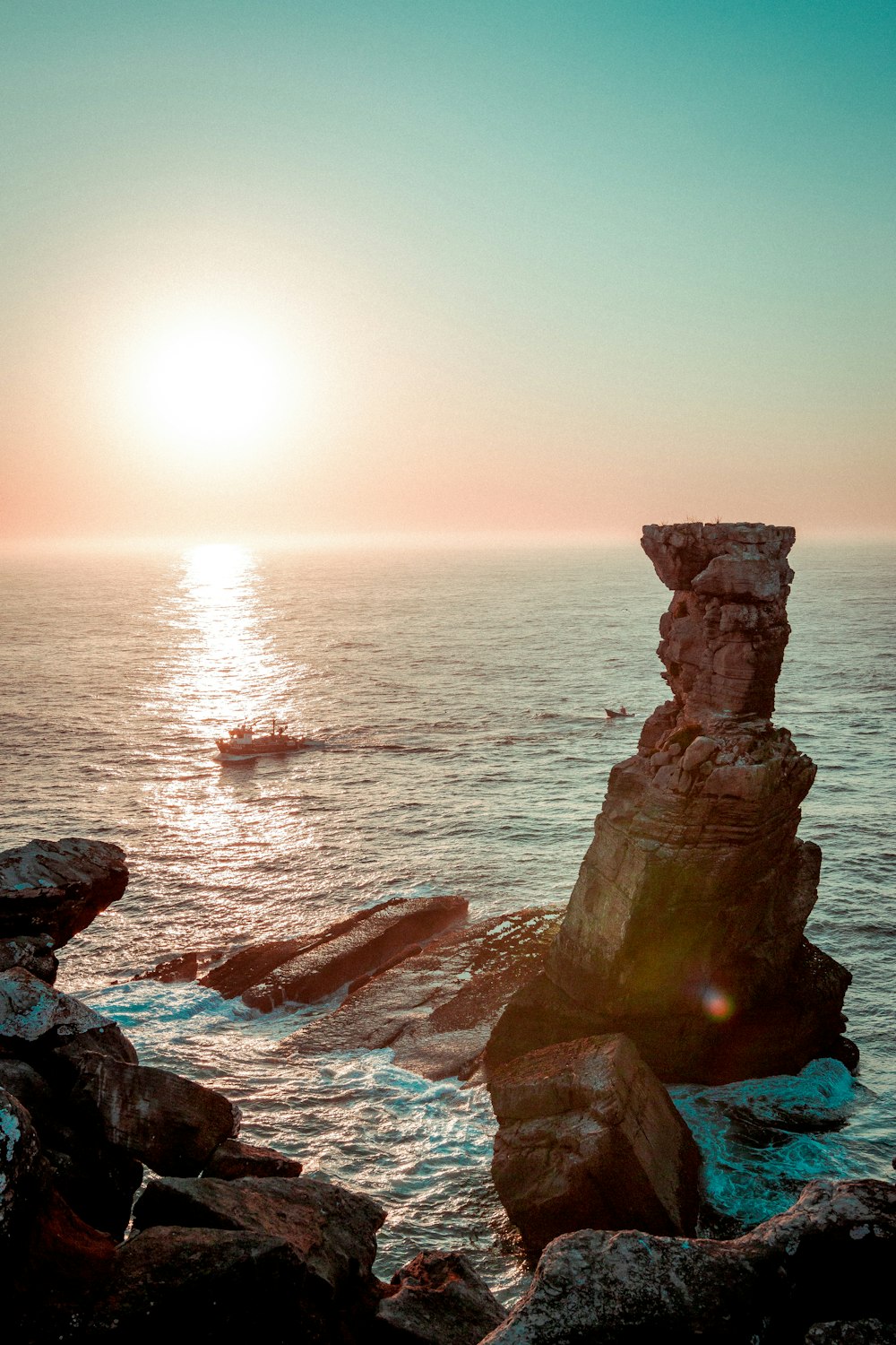 Formación de roca marrón en el mar durante la puesta del sol
