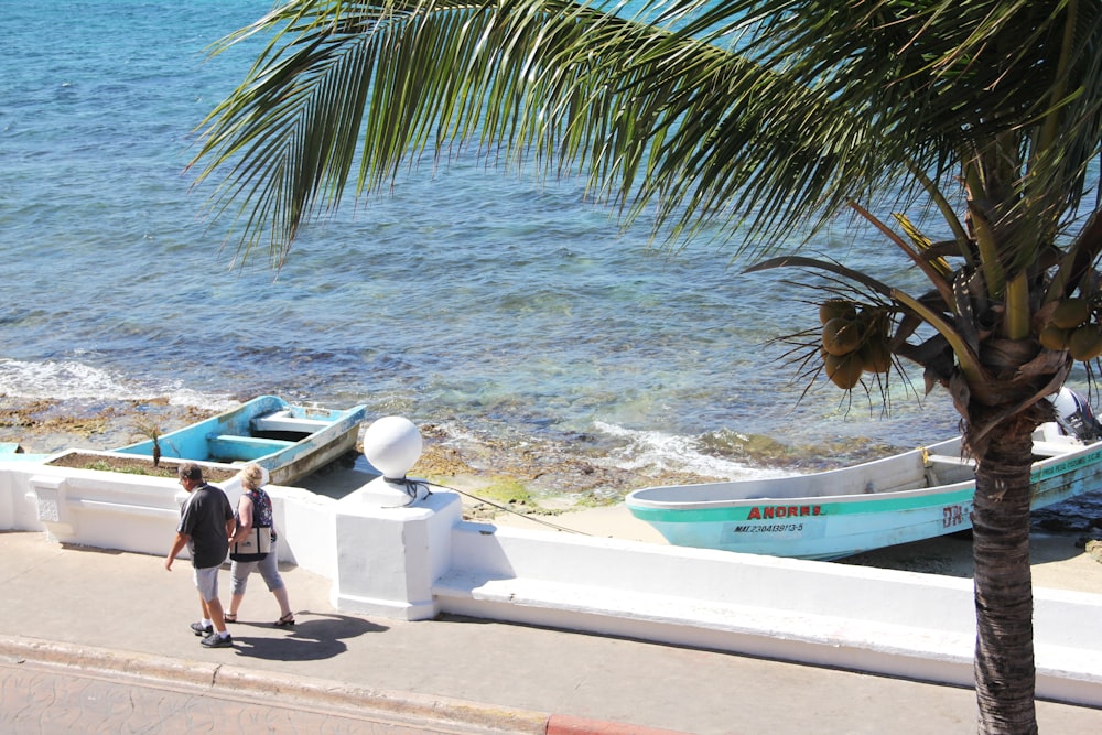 people sitting on white and blue boat on beach during daytime