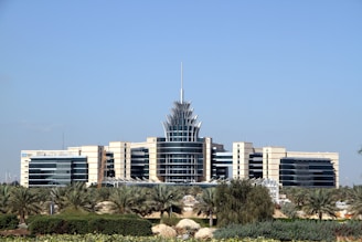 white and blue concrete building near green trees under blue sky during daytime