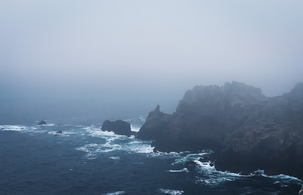 black rock formation on sea during daytime