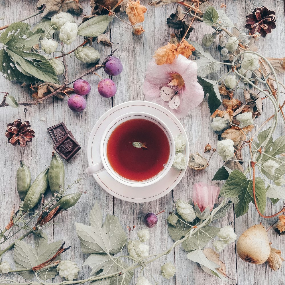 petali di fiori bianchi e rosa accanto a tazza in ceramica rossa e bianca