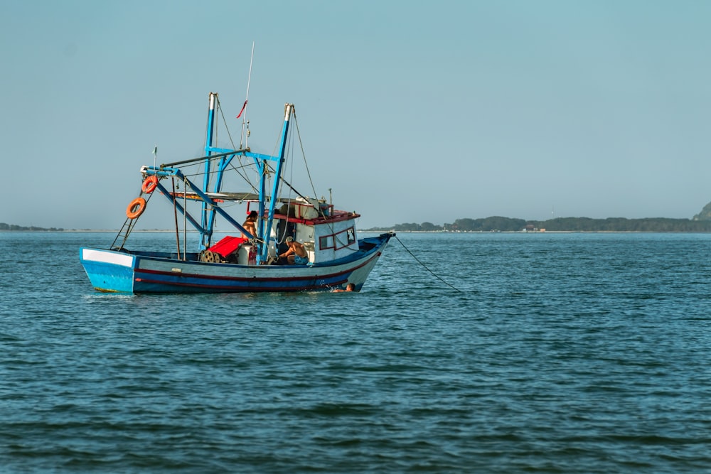 blue and red boat on sea during daytime